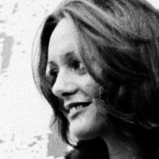 Woman smiling indoors near abstract wall art.