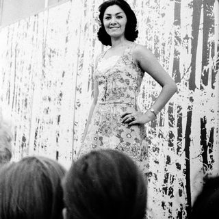 Elegant woman in floral dress posing on stage.