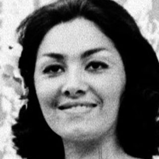 Elegant woman in floral dress posing on stage.