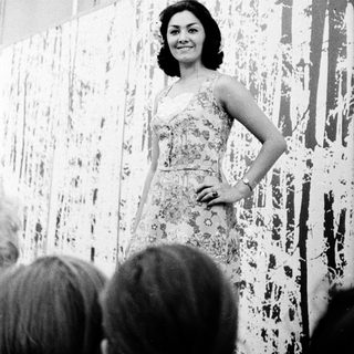 Elegant woman in floral dress posing on stage.