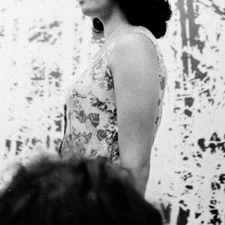 Woman speaking at an indoor event with abstract background.