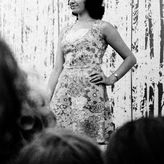 Woman posing in front of abstract art exhibit.