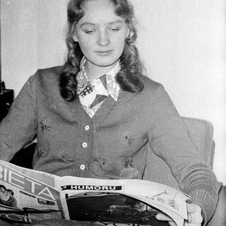 Woman reading newspaper in vintage clothing.