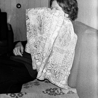 Person hiding face with patterned cloth indoors.