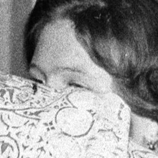 Person hiding face with patterned cloth indoors.