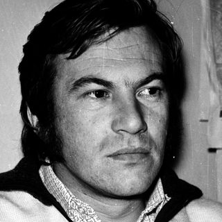 Man in vintage sweater, serious expression.