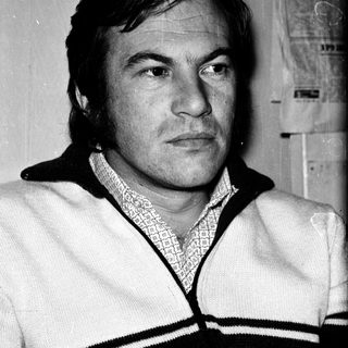 Man in vintage sweater, serious expression.