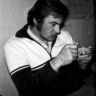 Man smoking cigarette indoors near calendar.