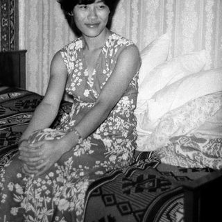 Black-and-white photo of woman sitting on bed.