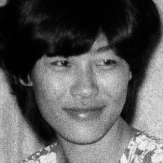 Black-and-white photo of woman sitting on bed.