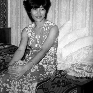 Black-and-white photo of woman sitting on bed.