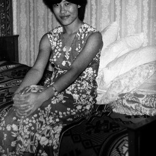 Black-and-white photo of woman sitting on bed.