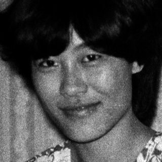 Black-and-white photo of woman sitting on bed.