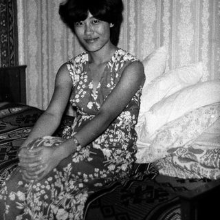 Black-and-white photo of woman sitting on bed.