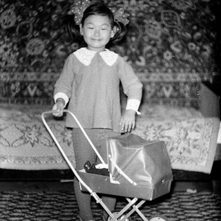 Young girl pushing toy stroller indoors.