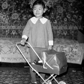Young child pushing toy stroller indoors.