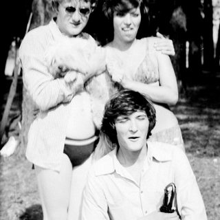 Three people posing outdoors in casual summer attire.