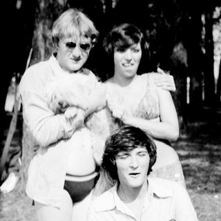 Three people posing outdoors in casual summer attire.