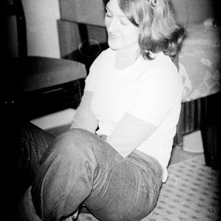 Woman sitting on bed, smiling, holding object.