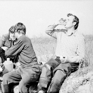 Four people camping outdoors, sharing food and conversation.