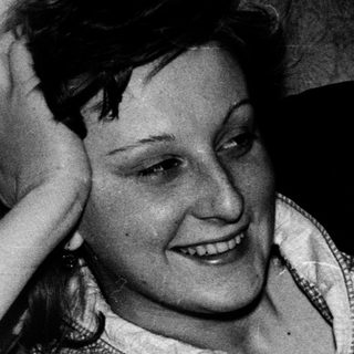 Smiling woman resting hand on head indoors.