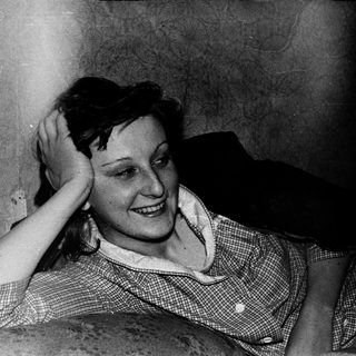 Smiling woman resting hand on head indoors.