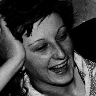 Woman laughing while resting her hand on her head.
