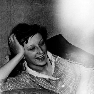 Woman laughing while resting her hand on her head.