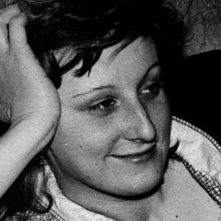 Woman resting hand on head indoors, mid-20th century.