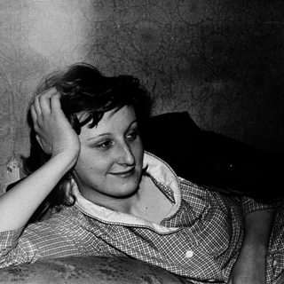 Woman resting hand on head indoors, mid-20th century.