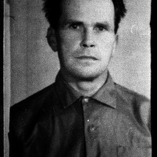 Portrait of a man in a formal, dark shirt.