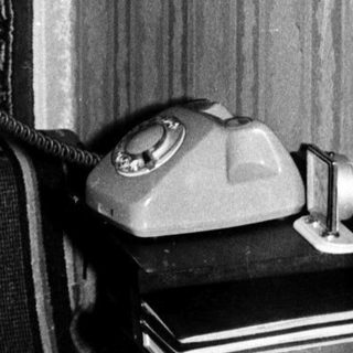 Man in uniform using vintage rotary phone.
