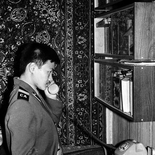 Man in uniform using vintage rotary phone.