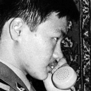 Man in uniform using vintage rotary phone.