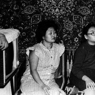 Family members in 1960s-style living room with bookshelf.