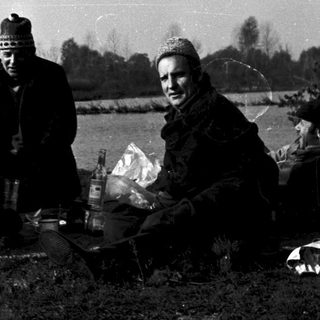 People picnicking outdoors by a lake.