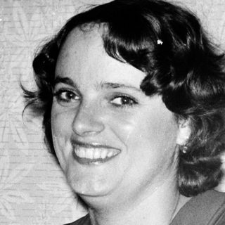 Young woman smiling in vintage-style dress, seated.