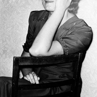 Young woman posing thoughtfully in vintage-style clothing.