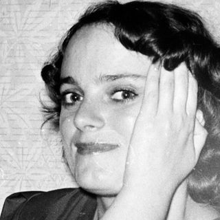 Young woman posing thoughtfully in vintage-style clothing.