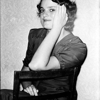 Young woman posing thoughtfully in vintage-style clothing.