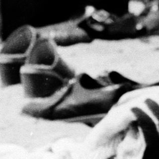 Woman writing on beach towel at outdoor gathering.
