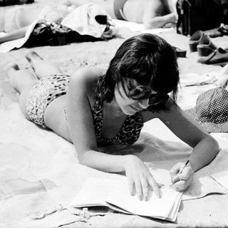 Woman writing on beach towel at outdoor gathering.