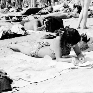 Beach scene with people sunbathing and relaxing.