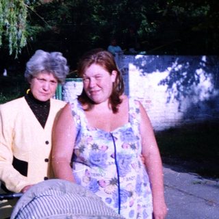 Two women walking together outdoors near water.