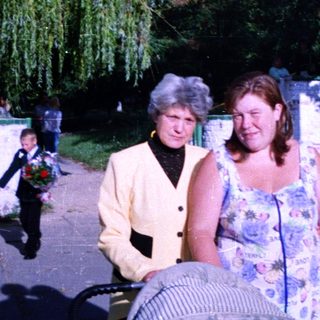 Two women walking together outdoors near water.