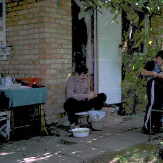 People washing dishes outdoors in backyard.