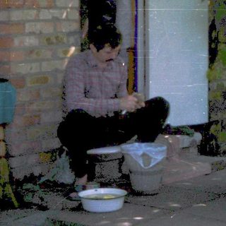 People washing dishes outdoors in backyard.