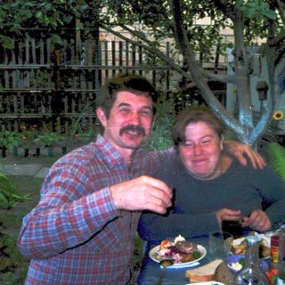 Two people enjoying meal outdoors with drinks.