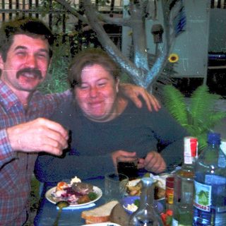 Two people enjoying meal outdoors with drinks.