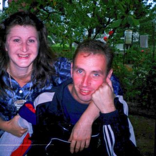Two people smiling outdoors at night.